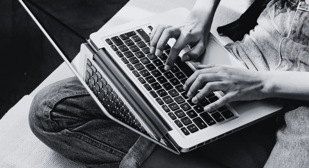Person tippt auf einem Laptop